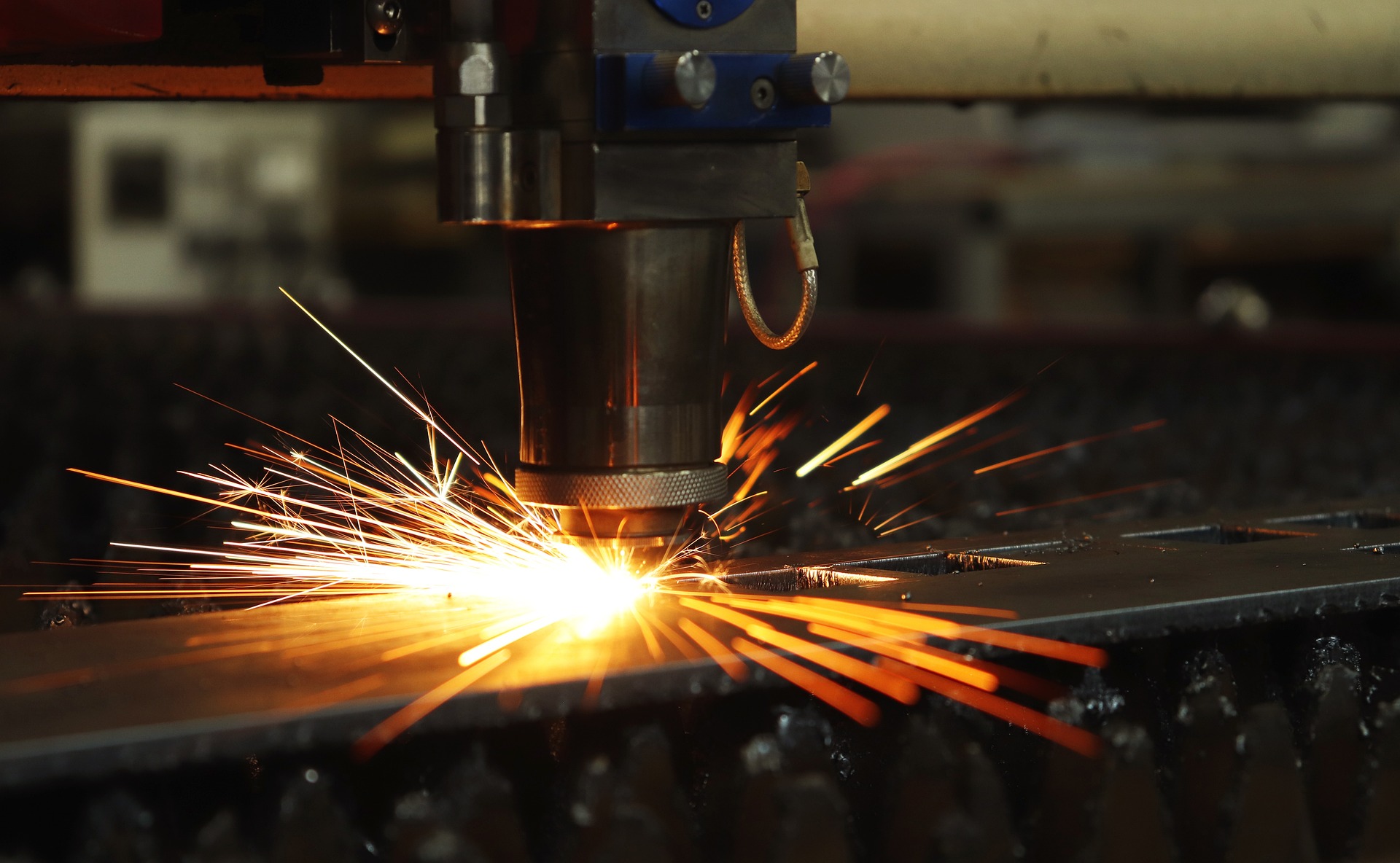 Nahaufnahme eines Metallbearbeitungsgeräts, das Funken beim Schneiden eines Metallblechs erzeugt